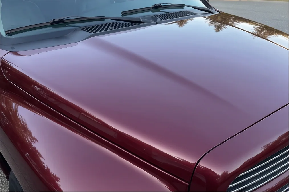 Same burgundy pickup hood with refined gloss after ceramic coating preparation in Chilliwack, BC