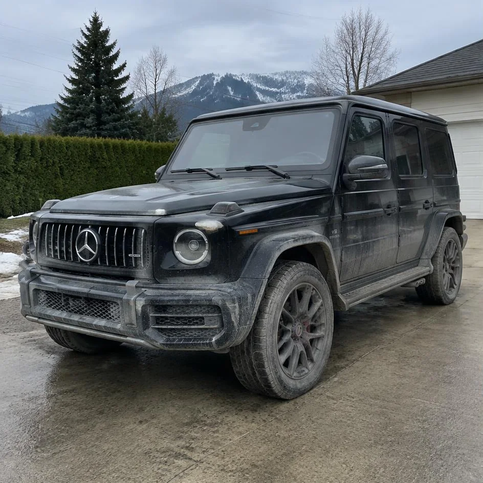 Black SUV before exterior detailing with winter road film, salt and dirty wheels in Chilliwack, BC