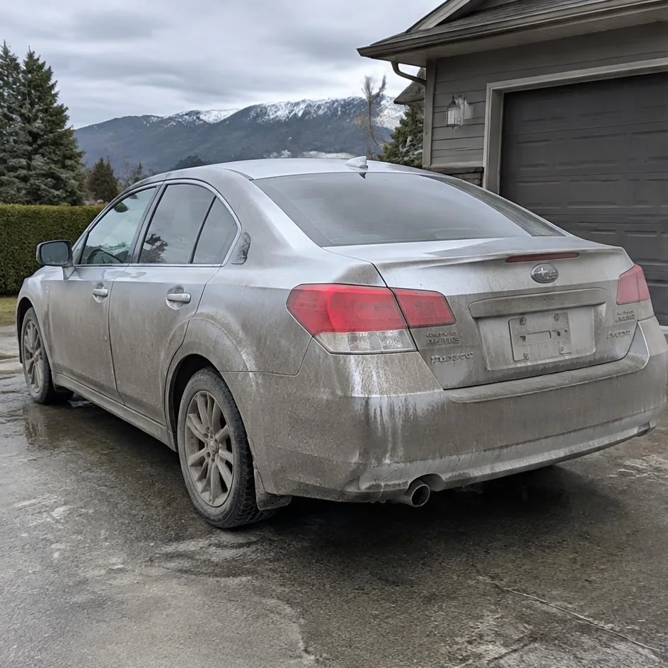 Silver sedan before exterior detailing with road film and dirt across the rear panels in Chilliwack, BC