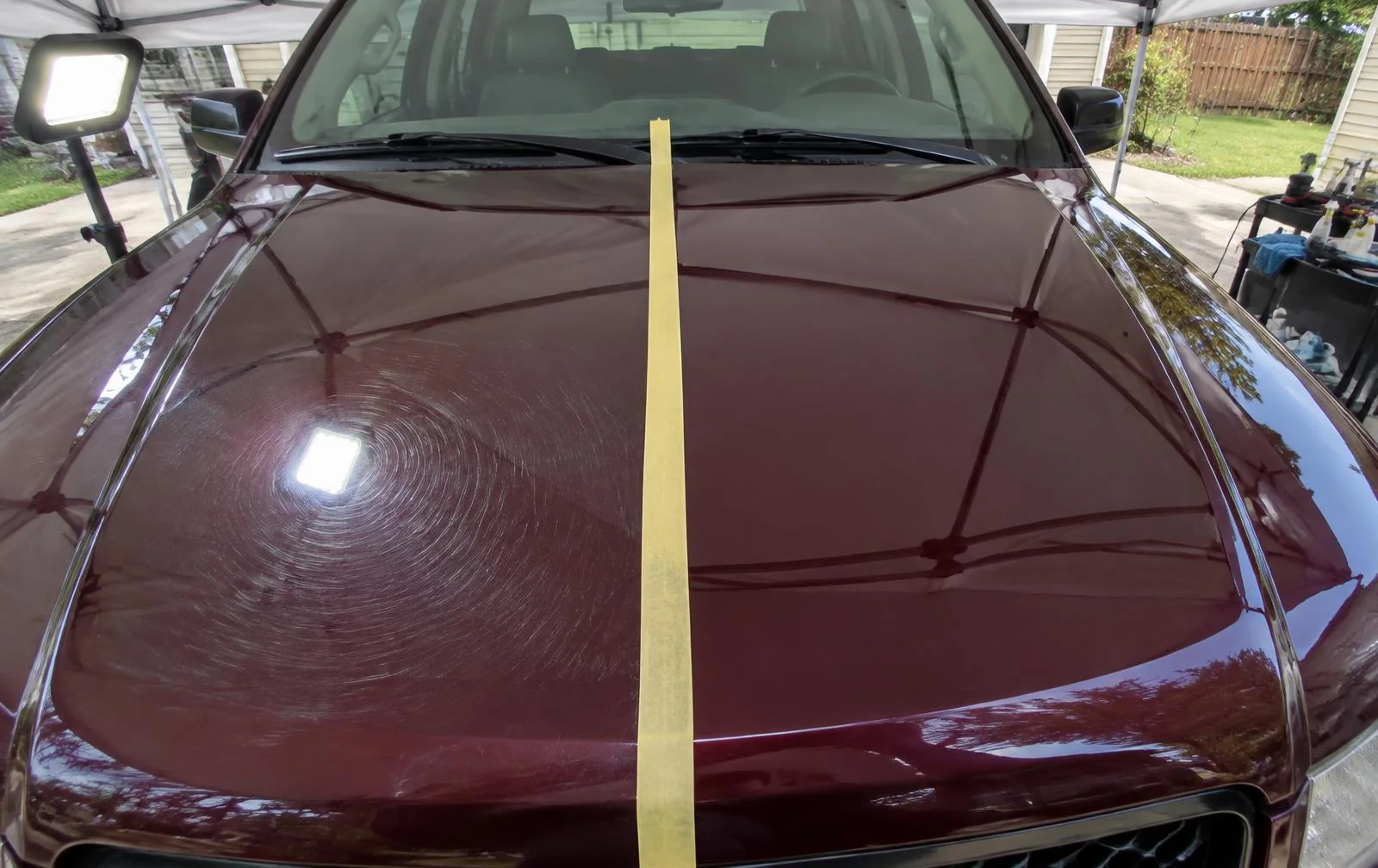 Paint correction 50/50 comparison showing swirled and polished sides of a burgundy hood in Chilliwack, BC